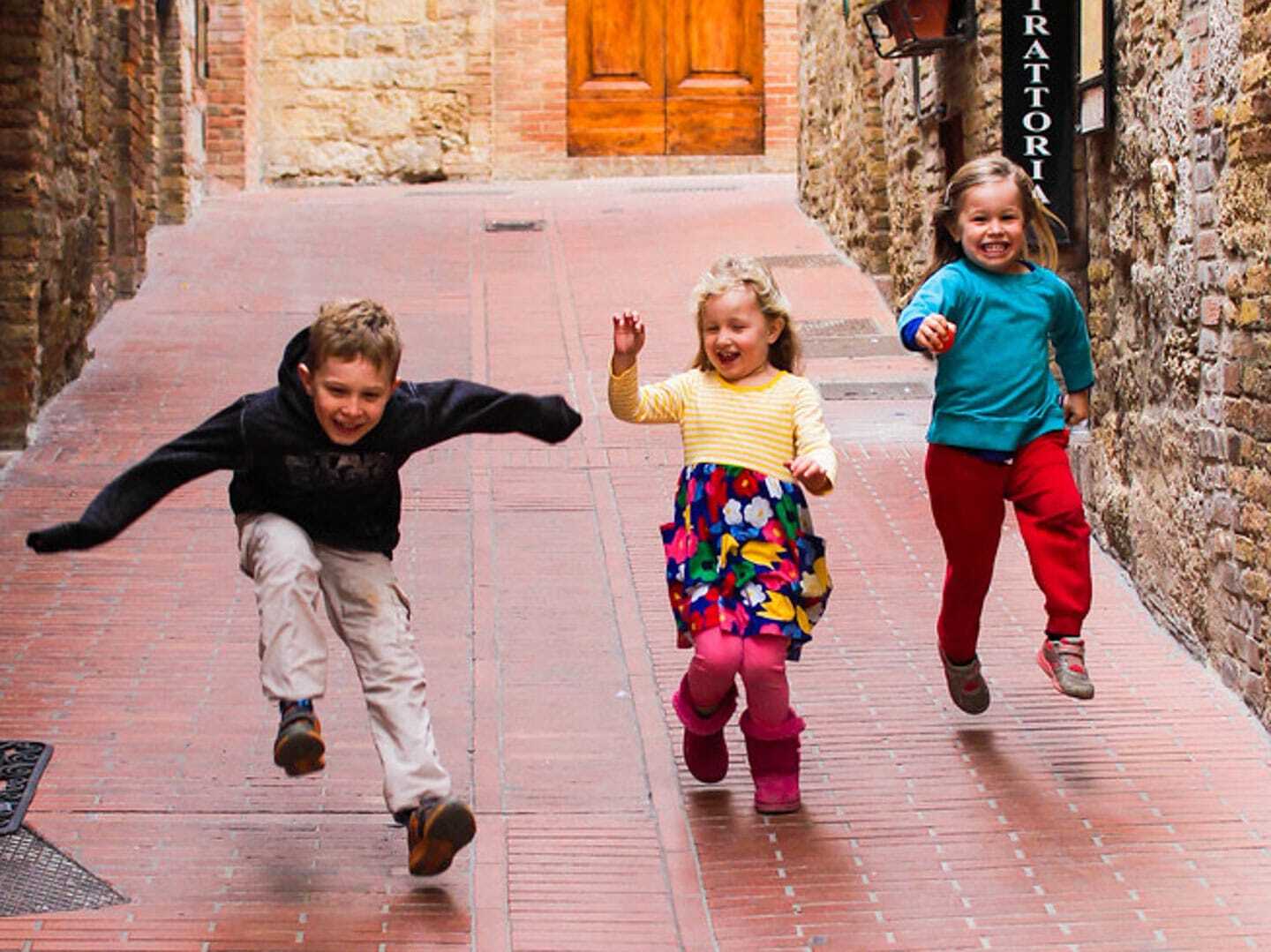 Three siblings running in street